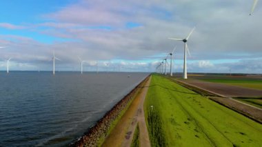 İlkbaharda Hollanda 'daki yel değirmeni parkı, yel değirmeninin hava görüntüsü elektrik üreten türbinler, Hollanda' daki bir hendekte bir sıra yel değirmeni türbini.