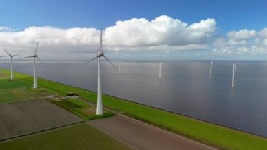 Baharda Hollanda 'daki yel değirmeni parkı, yel değirmeninin hava görüntüsü elektrik üreten türbinler, okyanusta yel değirmenleri.