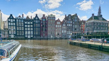 Arka planda yüksek binalarla çevrili bir nehirde zarifçe yüzen bir teknenin görüntüsü. Amsterdam Hollanda 21 Nisan 2024