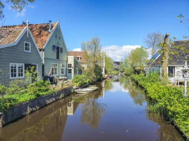 Sakin bir nehir, berrak mavi bir gökyüzü altında canlı yaprakları ve yuvarlanan tepeleri olan yemyeşil bir kırsal bölgeden huzur içinde akar. Waterland Hollanda 'da Broek 