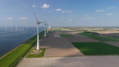 Kıyıdaki yel değirmeni bulutları ve mavi gökyüzü, yel değirmeni türbinleri okyanusta yeşil enerji üretir. Hollanda 'da yaz aylarında enerji geçişi