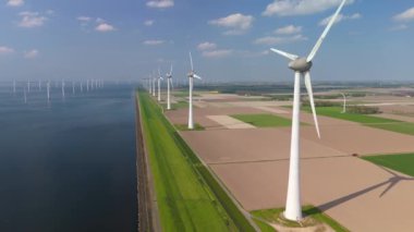 Kıyıdaki yel değirmeni bulutları ve mavi gökyüzü, yel değirmeni türbinleri okyanusta yeşil enerji üretir. Hollanda 'da enerji geçişi, Flevoland' da bir dizi yel değirmeni türbini