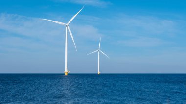 Uçsuz bucaksız okyanusta iki görkemli rüzgar türbini, rüzgarın gücünü yakalıyor ve Hollanda için yenilenebilir enerji üretiyor. Dünya Günü, boşluğu kopyala