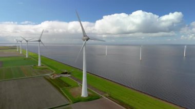 Hollanda 'daki yel değirmeni parkı, yel değirmeni türbinlerinin hava görüntüsü elektrik üreten yeşil enerji, Hollandalı bir hendekte ve okyanusta yel değirmenleri.