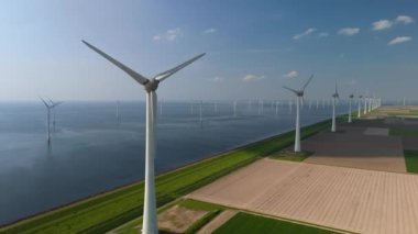  Yeşil çayır, bulutlar ve mavi gökyüzü olan yel değirmeni parkı, yel değirmeni türbinleri okyanusta yeşil enerji üretir. Hollanda Avrupa 'sında enerji geçişi