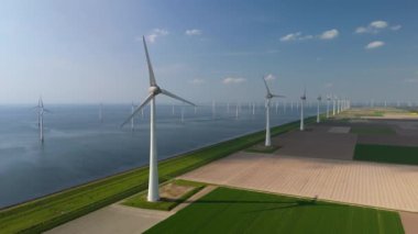 Kıyıdaki yel değirmeni bulutları ve mavi gökyüzü, yel değirmeni türbinleri okyanusta yeşil enerji üretir. Hollanda Avrupa 'sında enerji geçişi