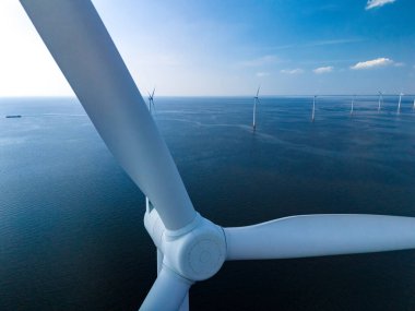 Okyanustaki bir rüzgar çiftliğinin nefes kesici hava manzarası, Hollanda Flevoland 'ında yenilenebilir enerji üreten yel değirmeni türbinlerinin sıralarını gösteriyor..