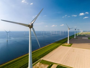 Hollanda 'da Flevoland' ın sakin sularının yanında gururla duran yüksek rüzgar türbinleri..
