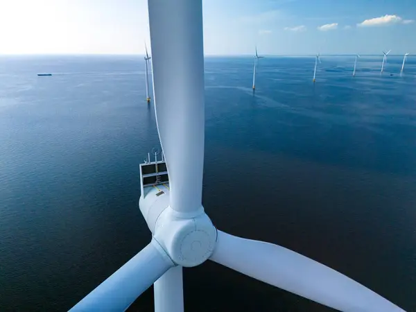 stock image A majestic wind turbine stands tall in the middle of the ocean, harnessing the power of the wind to generate clean, sustainable energy for the surrounding area.