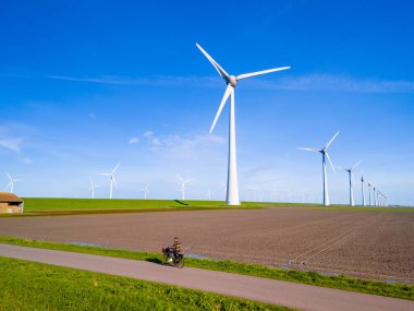 Hollanda, Flevoland 'daki bir rüzgar çiftliğinin çok sayıda yel değirmeninin bahar esintisinde döndüğü pitoresk bir manzarası. Yel değirmeni türbinleri, yeşil enerji, çevre dostu, Dünya günü