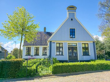 Waterlands Hollanda 'da Broek, 21 Nisan 2024, göz kamaştırıcı mavi çatılı ve pencereli beyaz bir ev berrak gökyüzüne karşı duruyor, büyüleyici bir cazibe ve zarafet.