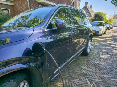 EV electric car in the concept of green energy and eco power produced from sustainable sources in the Netherlands, ev car charging outside a house clipart