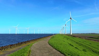 Baharda Hollanda 'daki yel değirmeni parkı, İjsselmeer Gölü kıyısındaki bir Hollanda hendeğinde yel değirmeni türbinlerinin insansız hava aracı görüntüsü.