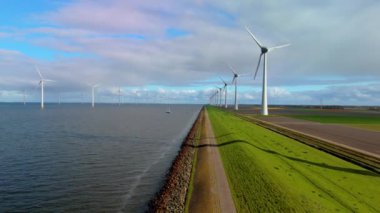 Baharda Hollanda 'daki yel değirmeni parkı, güneşli bir günde yeşil enerji üreten yel değirmeni türbinlerinin insansız hava görüntüsü.