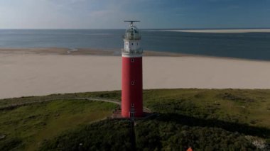 Yazın Wadden Adası 'nda kum tepeleri olan Hollanda Hollanda' nın batımında Texel deniz feneri. Gün batımında okyanusta gün batımında yukarıdan drone hava görüntüsü.