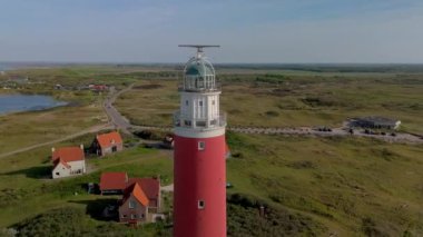 Yazın Wadden Adası 'nda kum tepeleri ve Cocksdorp ile birlikte güneş batarken Texel deniz feneri. İHA hava görüntüsü yukarıdan ikonik kırmızı deniz fenerinden