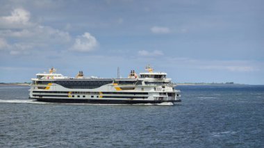 Texel Hollanda 12 Mayıs 2024, büyük bir feribot zarif bir şekilde Texel, Hollanda yakınlarındaki engin okyanus sularında yelken açar ve arkasında beyaz köpükten bir iz bırakır..