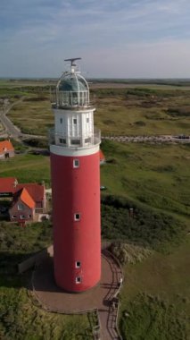Hollanda 'daki Wadden Adası' nda kum tepeleri olan Texel deniz feneri. Gün batımında okyanusta gün batımında yukarıdan drone hava görüntüsü.
