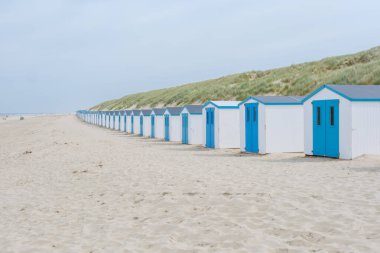 Hollanda, Texel 'in kumlu sahillerinde canlı mavi kapıları olan büyüleyici bir sahil kulübesi çizgisi resim gibi ve renkli bir manzara yaratıyor. De Koog Sahili Tekel