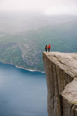 İki birey Preikestolen 'in kıyısında duruyor, Norveç' te dramatik bir uçurum, aşağıdaki fiyordun uçsuz bucaksız genişliğine bakıyor. Preikestolen, Norveç 'te kadın ve erkek coupe