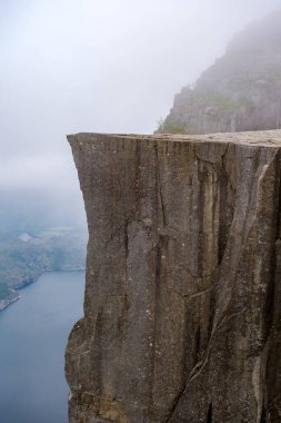 Preikestolen 'in kıyısından nefes kesici bir manzara, Norveç' te bir uçurum. Sisli manzara bir gizem ve ihtişam hissi yaratır..
