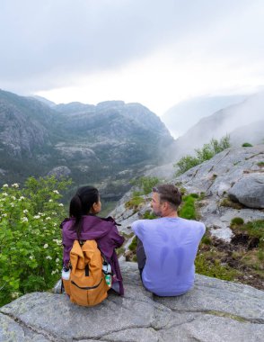 İki yürüyüşçü kayalık bir çıkıntıda oturur, aşağıdaki sisli vadiye bakarlar. Çift, Norveç 'in vahşi doğasında huzurlu bir yansımanın tadını çıkarıyor. Norveç, Preikestolen