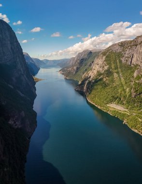 Norveç 'te derin, dar bir fiyordun nefes kesici hava manzarası, her iki tarafında sarp kayalıklar ve yukarıda parlak mavi bir gökyüzü. Kjerag, Lysebotn, Lysefjorden, Norveç