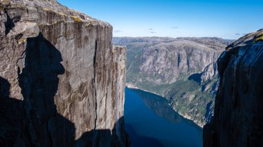 Norveç 'te sakin bir fiyorda tepeden bakan dramatik bir uçurumun panoramik görüntüsü. Kjeragbolten, Norveç