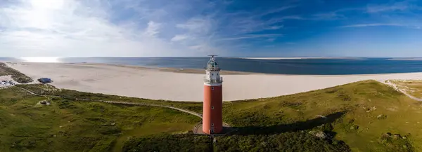 stock image A birds eye view of a tall lighthouse with a beacon shining brightly on a sandy beach, overlooking the vast ocean on the island of Texel, Netherlands.