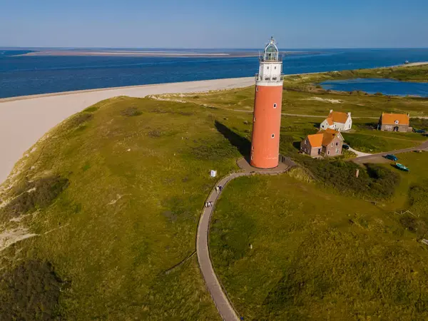 stock image Majestic lighthouse towering over sandy shores, overlooking the vast sea below, guiding ships safely through the night.