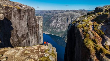 Norveç 'te Kjeragbolten, Norveç Kürsü Kayası' nın kenarında duran iki kişi çarpıcı manzarayı seyrediyor. Norveç, Kjeragbolten 'i ziyaret eden iki erkek ve kadın