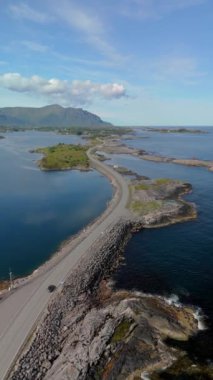 Atlantik Okyanusu Yolu, Atlanterhavsveien, Norveç bu çarpıcı hava manzarasında sakin bir su kütlesinin içinden geçen bir yol. Yolun ışıldayan sularda kayboluşunu izle, büyüleyici bir şey yarat.