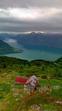 Bir çift Norveç 'te fiyorda bakan kayalık bir tepede oturuyor. Huzurlu manzara, Molden yürüyüşü, Norveç 'ten LustraFjord' un manzarasına hayran oldukları için onlar için huzurlu bir zemin oluşturuyor.