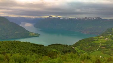Dağları ve ağaçları olan, bulutlu bir günde doğal güzelliği yansıtan, Molden Yürüyüşü 'nden LustraFjord, Sogn Norveç' ten barışçıl bir manzara yaratan, vadideki sakin bir gölün çarpıcı bir klibi.