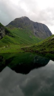  Bereketli yeşillik ve yüksek zirvelerle çevrili sakin bir göle yansıyan görkemli dağ manzarası nefes kesici bir doğal manzara yaratıyor, Norveçli fiyortlar Stavbergvatnet Urke