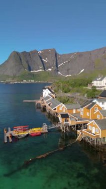 Norveç 'in Lofoten Adaları, Norveç' in tarihi Sakrisoy, Norveç, İskandinavya köyünde geleneksel sarı balıkçı Rorbuer kulübeleriyle yaz manzarası
