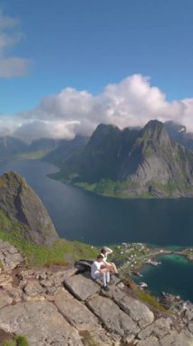 Reinebringen Dağı Lofoten Adaları 'nın tepesinde, Reinebringen' in tepesinde duran bir çift erkek ve kadın. Reine bakış açısına giden turistik yol, Reine, Lofoten, Norveç