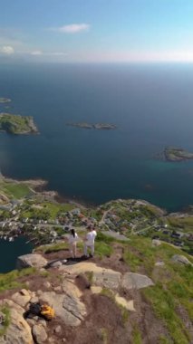 Reinebringen Lofoten Adaları 'nın tepesinde, Reinebringen' in tepesinde duran bir çift kadın ve erkek. Reine bakış açısına giden turistik yol, Reine, Lofoten, Norveç