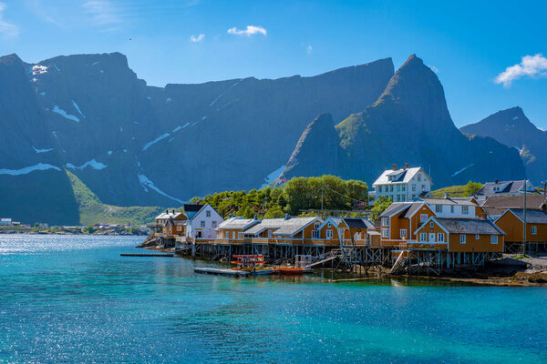 A picturesque view of a quaint Norwegian village with colorful houses built on stilts over the water. traditional yellow fisherman Rorbuer cabins in the village of Sakrisoy, Norway, Scandinavia