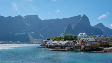 Norveç 'in Lofoten Adaları kıyısında, geleneksel ahşap evleri ve görkemli dağların zeminine kurulmuş pitoresk bir köy. Sarı balıkçı Rorbuer kulübeleri, Sakrisoy, Lofoten