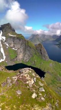 Reinebringen Lofoten Adaları 'nın tepesinde, Reinebringen' in tepesinde duran bir çift kadın ve erkek. Reine bakış açısına giden turistik yürüyüş yolu, Reine, Lofoten, Norveç