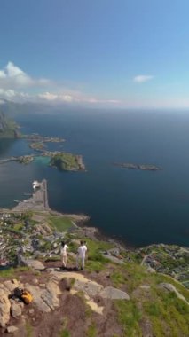Reinebringen Lofoten Adaları 'nın tepesinde, Reinebringen' in tepesinde duran bir çift kadın ve erkek. Reine bakış açısına giden turistik yol, Reine, Lofoten, Norveç