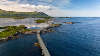 Norveç 'teki Atlantic Road Köprüsü' nün havadan görünüşü, küçük adaları birbirine bağlıyor. Turkuaz sular, uzak dağları olan yemyeşil adalarda esiyor..