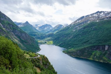 Yeşil vadileri ve Norveç 'teki görkemli fiyort boyunca kıvrılan dolambaçlı bir yolun manzarası. Norveç 'in Geiranger' si