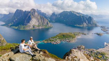 Bir çift Norveç 'te güzel Lofoten Adaları' na bakan bir dağın tepesinde oturuyor. Manzarada muhteşem dağlar, fiyortlar ve Reinebringen, Lofoten manzarasına yuva yapmış küçük bir kasaba yer alıyor.