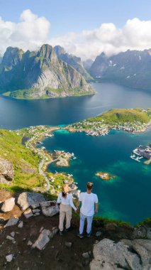 Norveç 'in Lofoten Adaları' nda muhteşem bir fiyorda bakan bir çift dağın kenarında duruyor. Reinebringen, Lofoten, Norveç 'te yürüyüş yapan çeşitli erkek ve kadınlar.