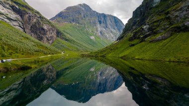 Norveç 'in yüksek dağlarının arasına yerleşmiş dingin bir göl durgun sularındaki manzaranın güzelliğini yansıtıyor..