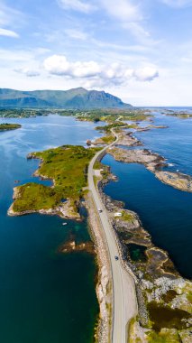 Norveç 'te berrak mavi su ve yemyeşil bitki örtüsüyle yılan gibi kıvrılan bir yolun havadan görünüşü. Atlantik Okyanusu Yolu Norveç