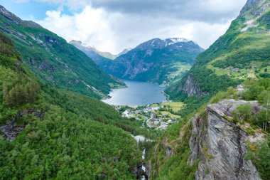 Resimli bir Norveç fiyordunun panoramik görüntüsü dramatik uçurumları, yemyeşil ve sakin mavi suları gözler önüne seriyor. Norveç 'in Geiranger' si