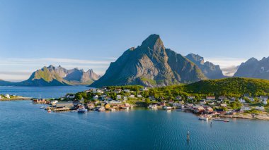 Norveç 'te yükselen dağlar ve berrak mavi denizle çevrili küçük bir köyün hava manzarası. Reine, Lofoten, Norveç